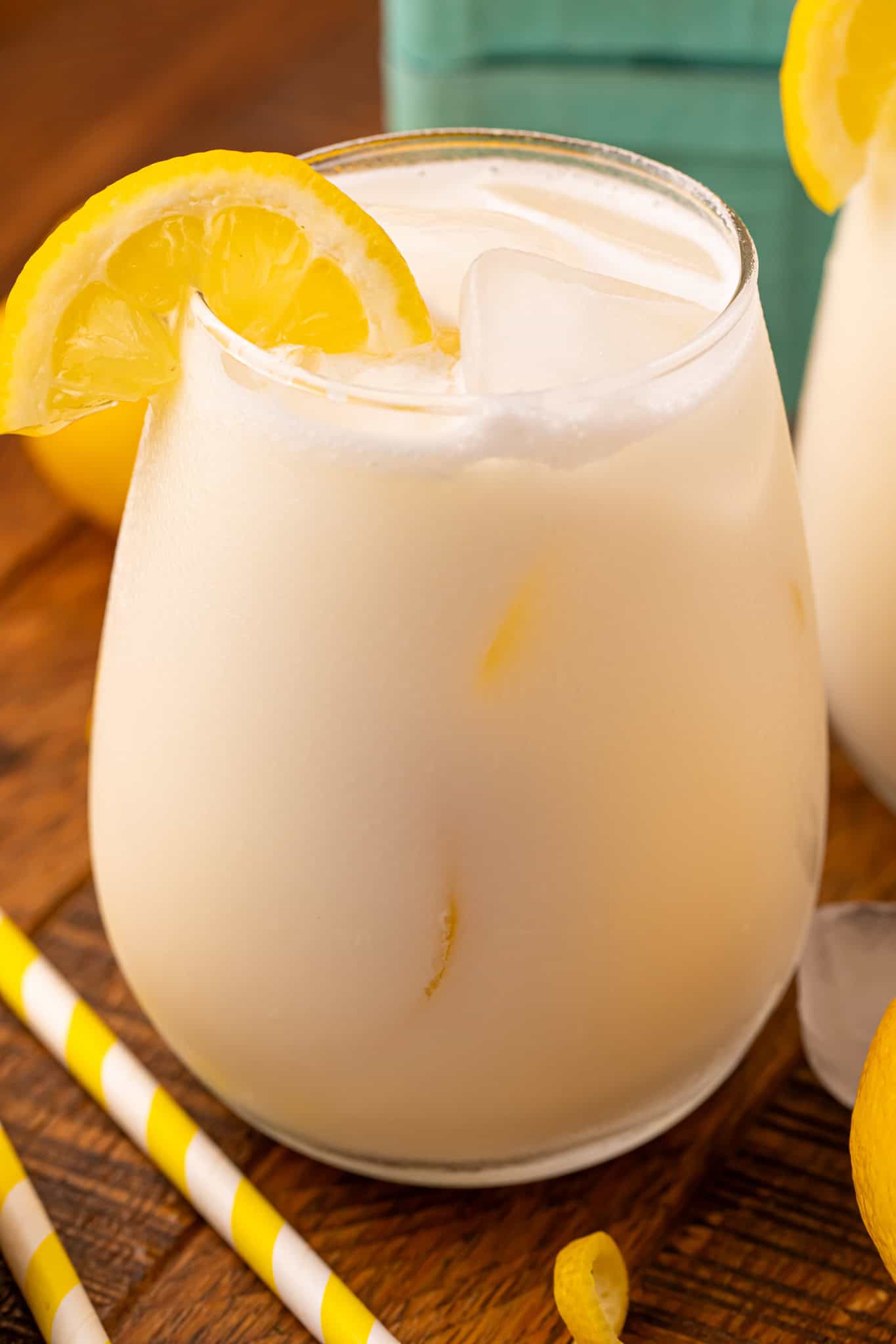 Headon view of creamy lemonade in a glass with ice cubes and a slice of lemon.