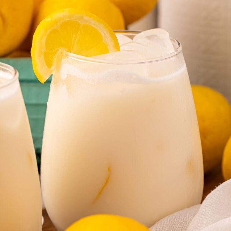 Creamy Lemonade in a glass with ice and lemon slice garnish on edge of glass.