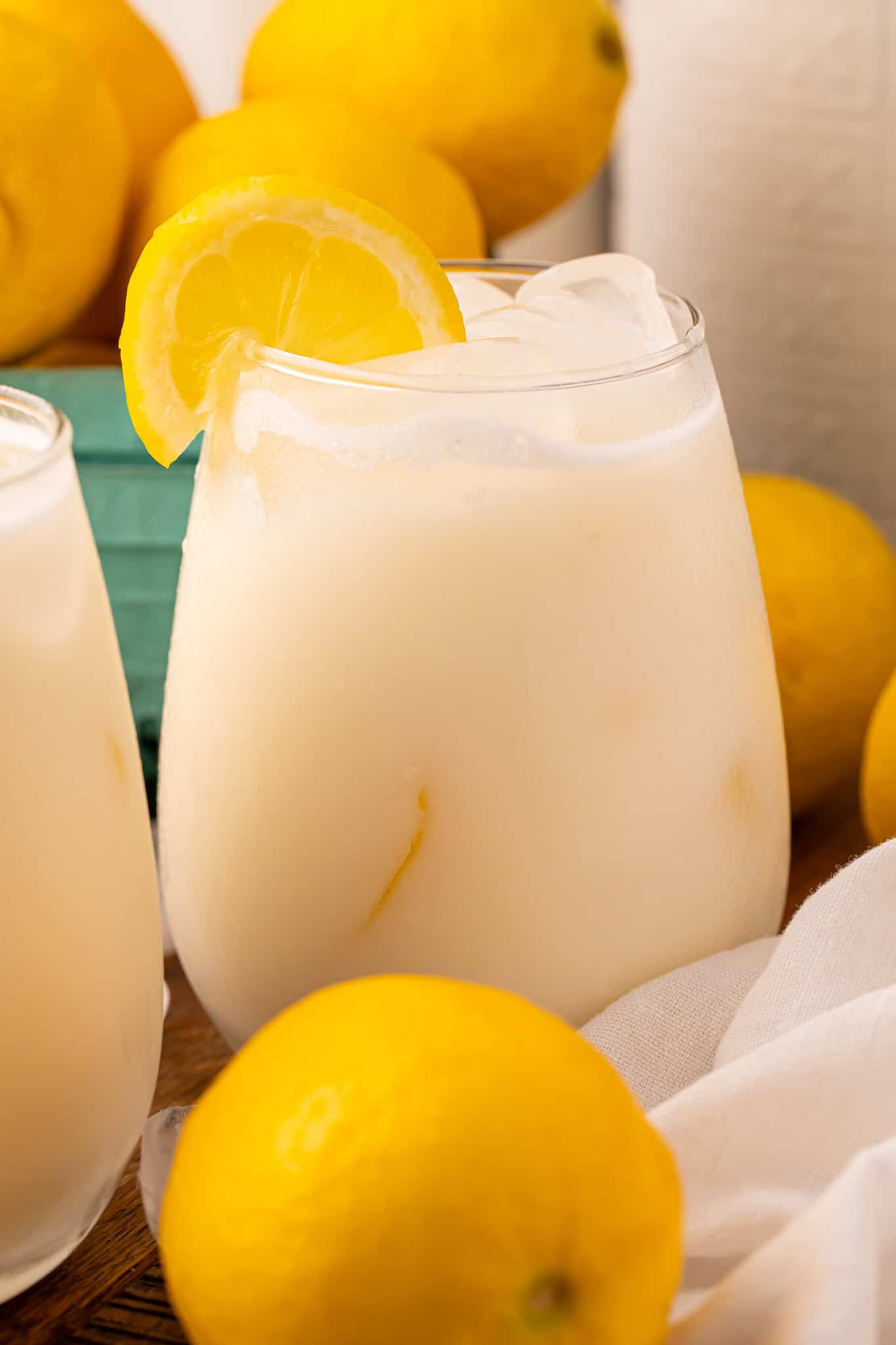 Head-on view of Creamy Lemonade in a glass with ice cubes and a lemon slice on the side of the glass.
