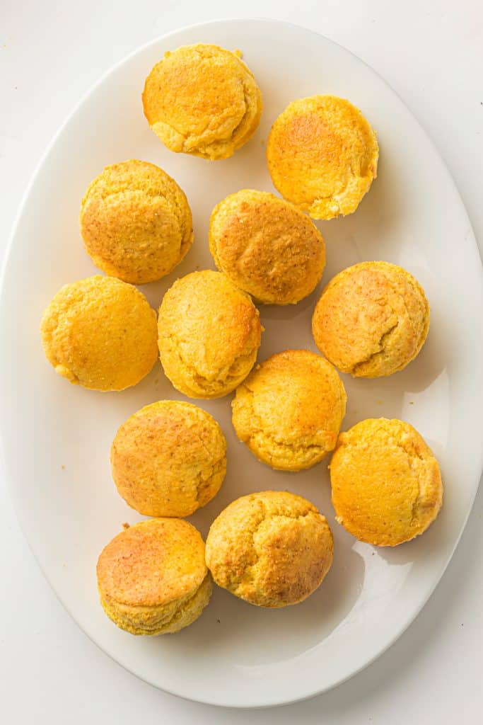 Overhead view of cornbread muffins on a white platter.