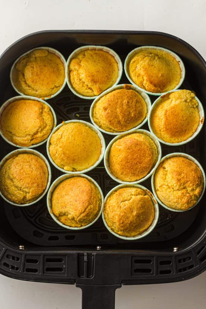 Overhead view of cornbread muffins in air fryer basket.