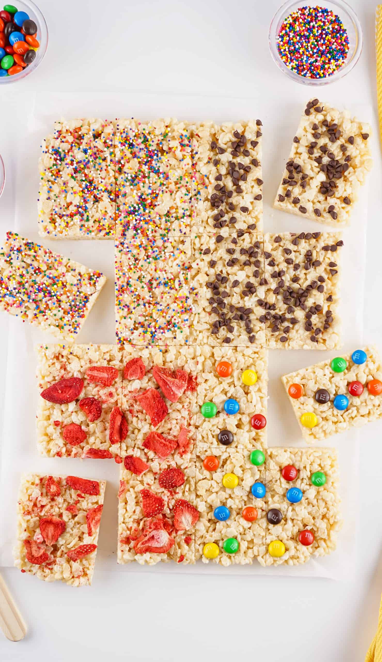 Overhead view of Rice Krispies Treats with toppings on them including dried strawberries, sprinkles, M &M's and chocolate chips.