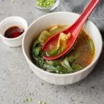 Bowl of Bok Choy Soup with red ladle spoon in it.