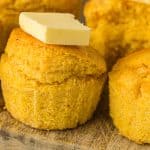 Headon view of cornbread muffin with pat of butter on top of it.