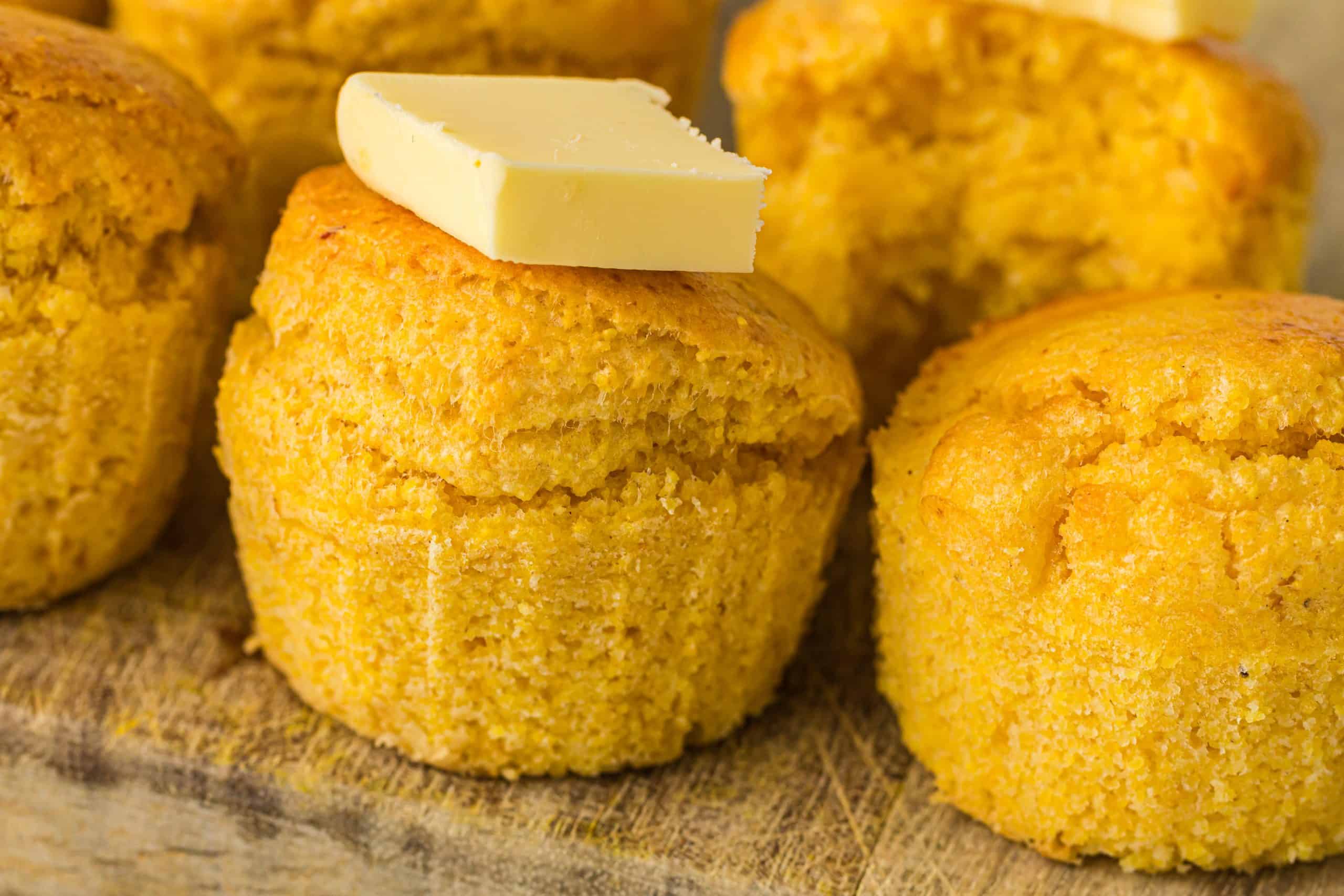 Headon view of cornbread muffin with pat of butter on top of it.