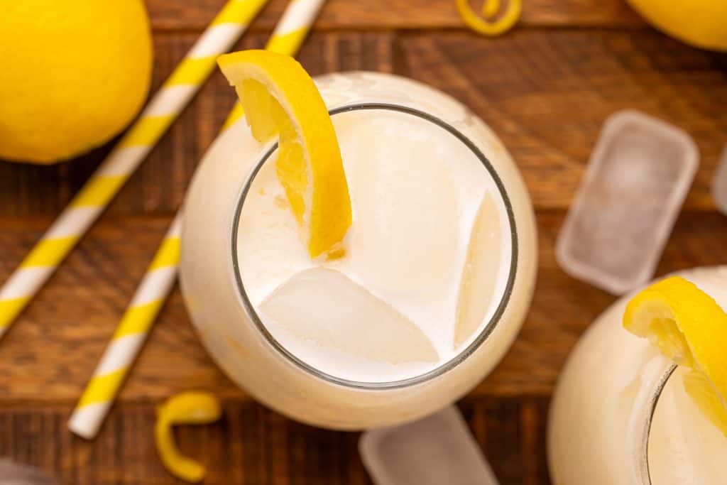 Overhead view of creamy lemonade with ice cubes and a lemon slice.