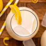 Overhead view of creamy lemonade with ice cubes and a lemon slice.