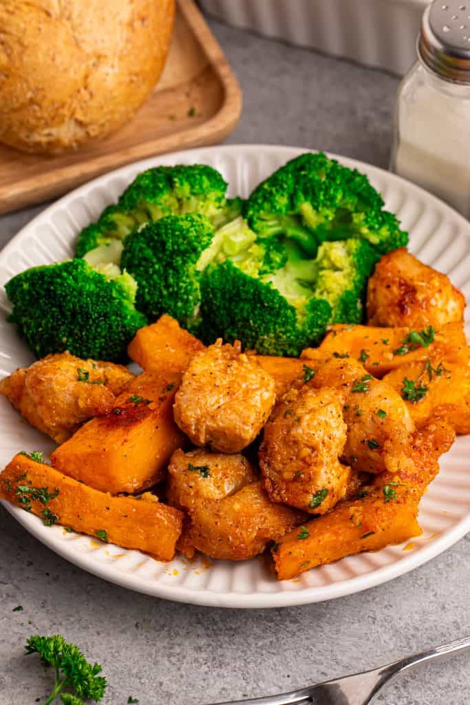 White plate with sweet potatoes, chicken and broccoli.