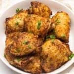 Overhead view of air fryer chicken thighs on a white plate.