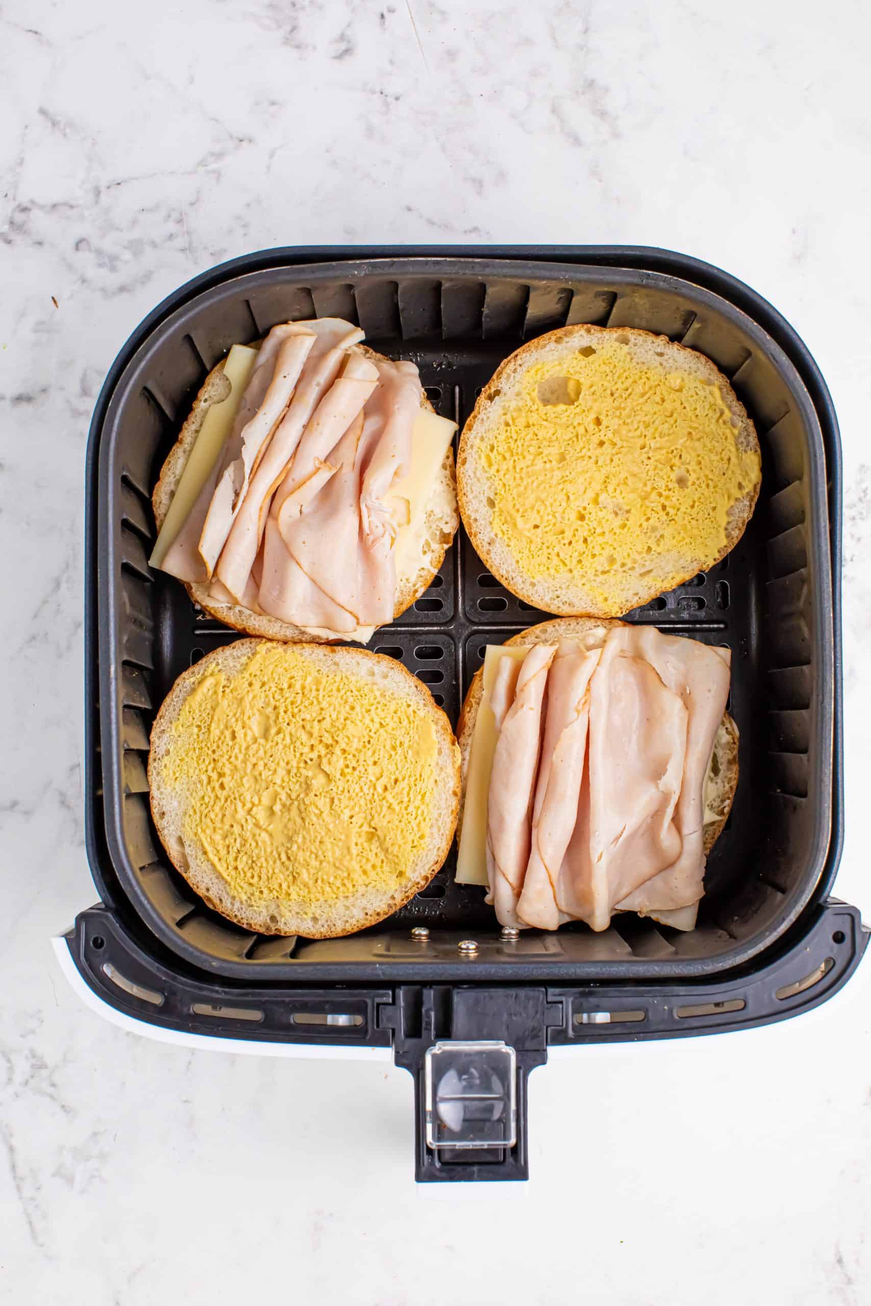 Overhead view of Brioche buns with sliced turkey on top in the air fryer.