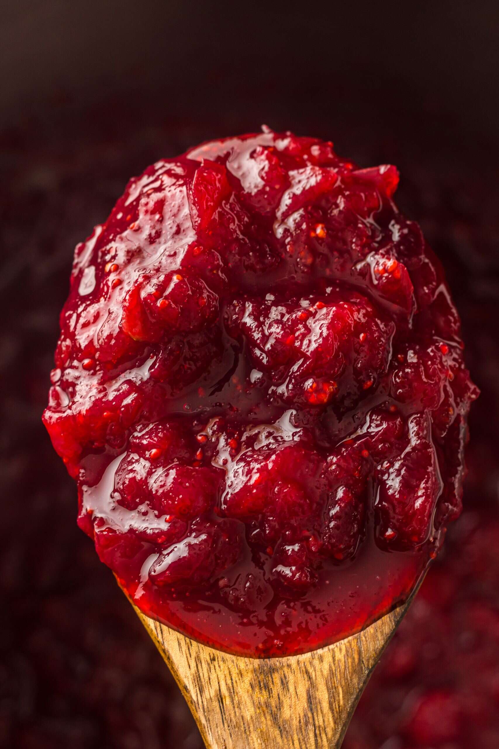 Cranberry sauce cooked in Instant Pot on wood spoon.