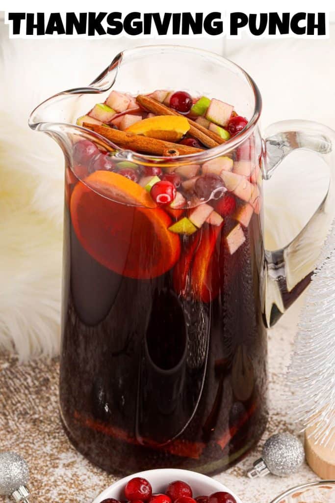 Thanksgiving Punch in a glass pitcher with fruit on top and text overlay. Pin for Pinterest.
