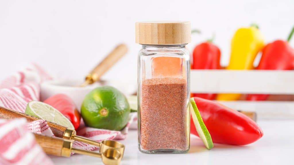 Tajin seasoning in a clear glass spice bottle.