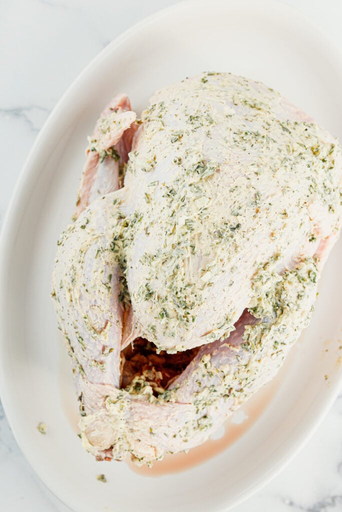 Overhead view of turkey rubbed with butter and herbs.