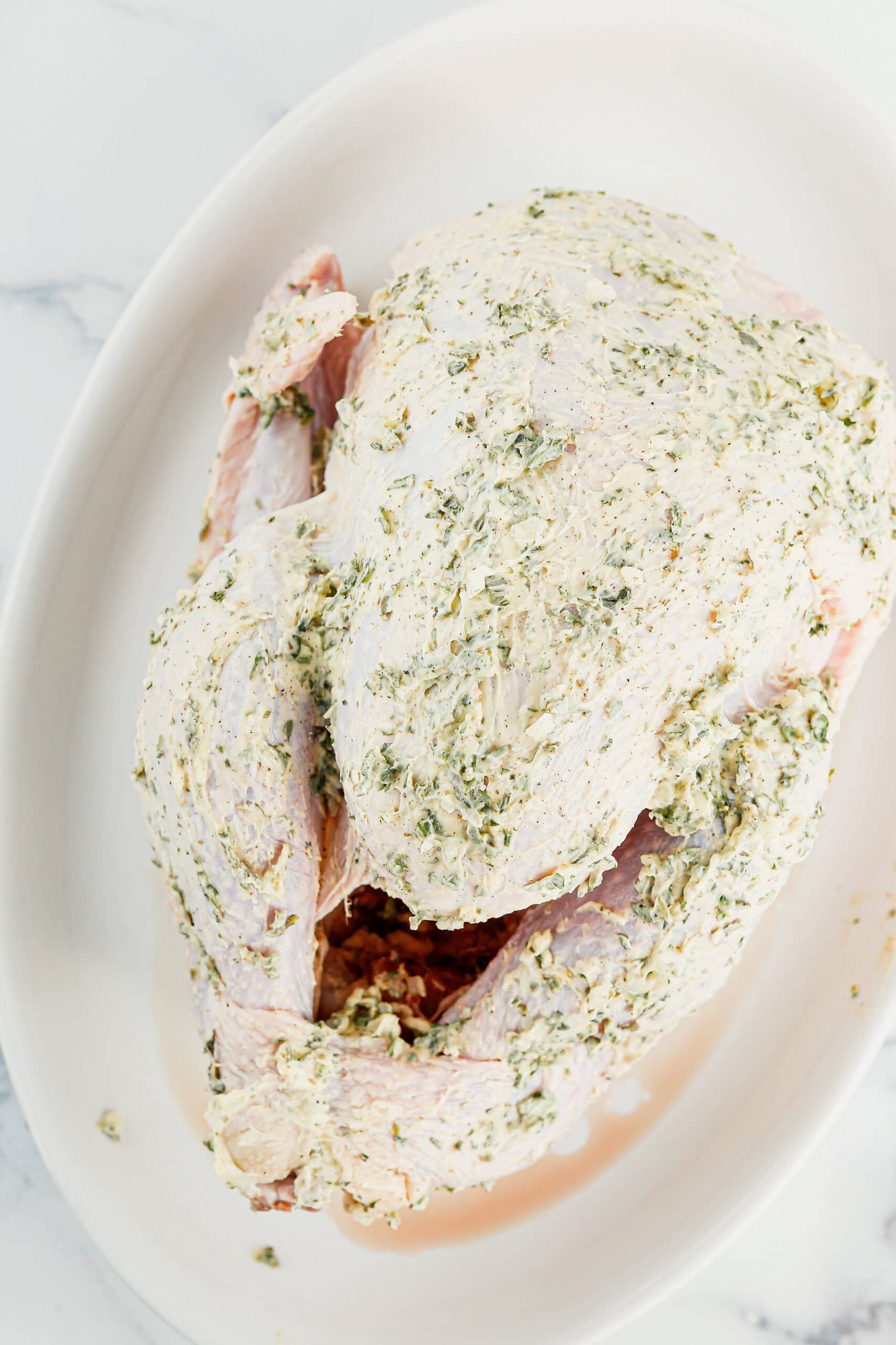 Overhead view of turkey rubbed with butter and herbs.