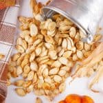Roasted pumpkin seeds poured out of small tin bucket