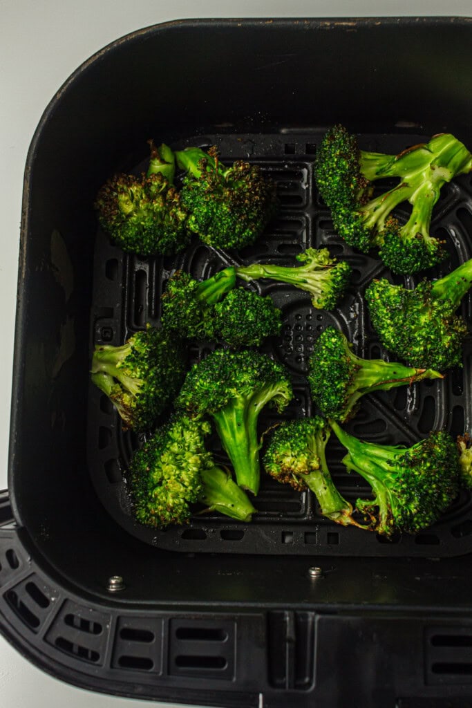 Overhead view of roasted broccoli in air fryer basket.