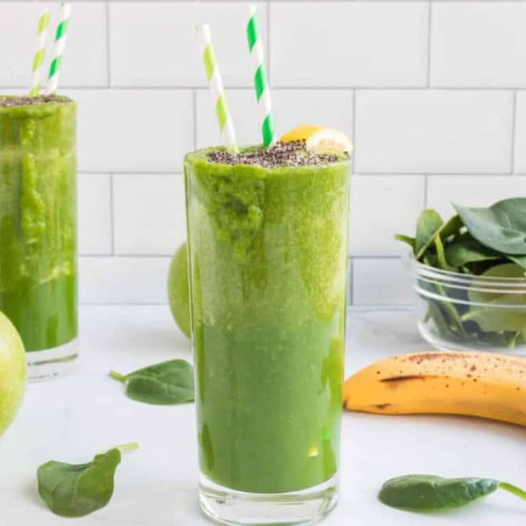 Green Apple Smoothie with striped straws in it and a lemon wedge and chia seeds on top.