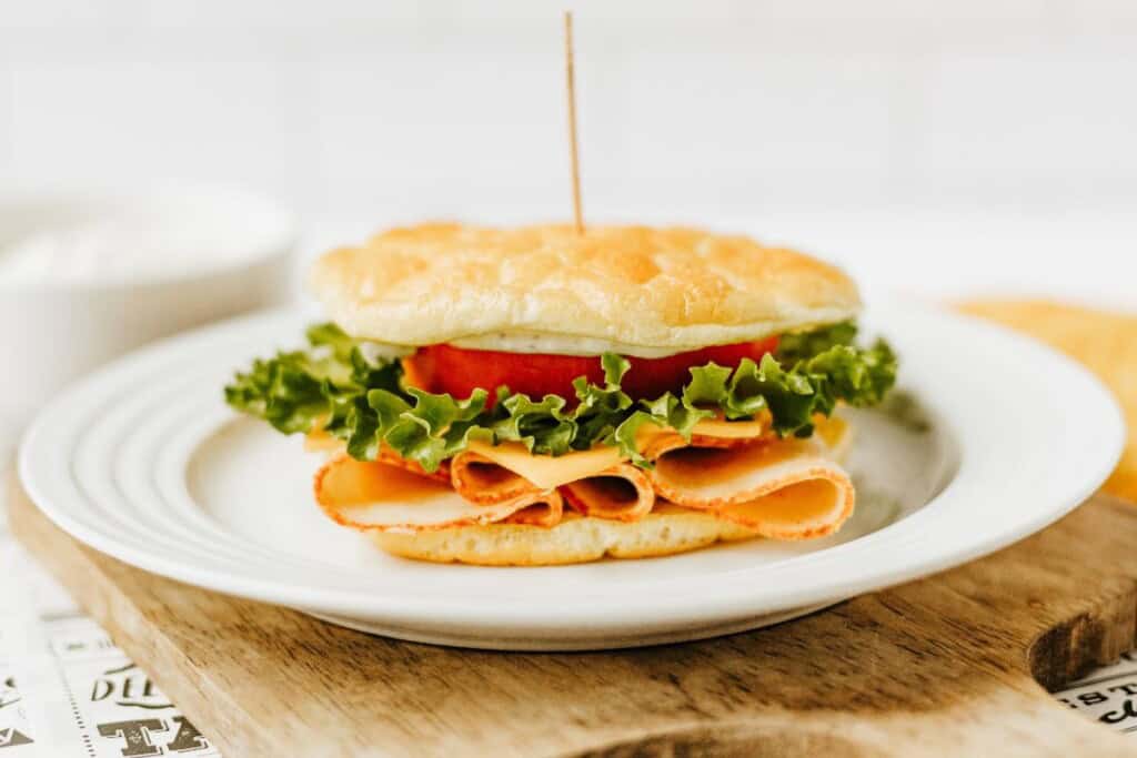 Cottage cheese cloud bread used as buns for a turkey, cheese, lettuce, and tomato sandwich