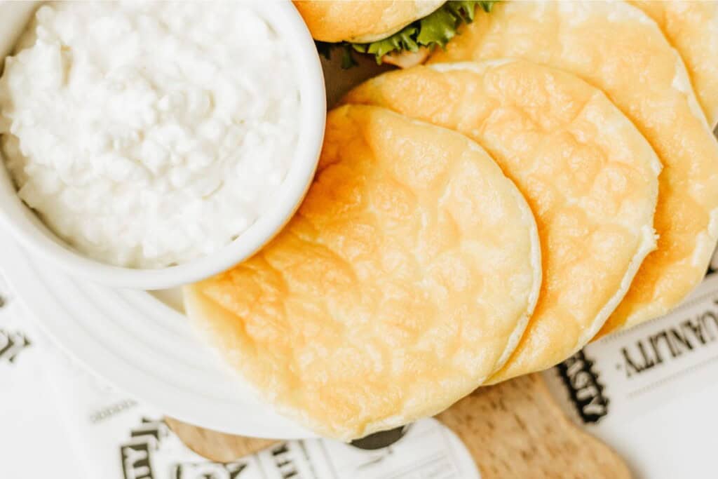 Fanned cottage cheese cloud bread rounds beside a bowl of cottage cheese