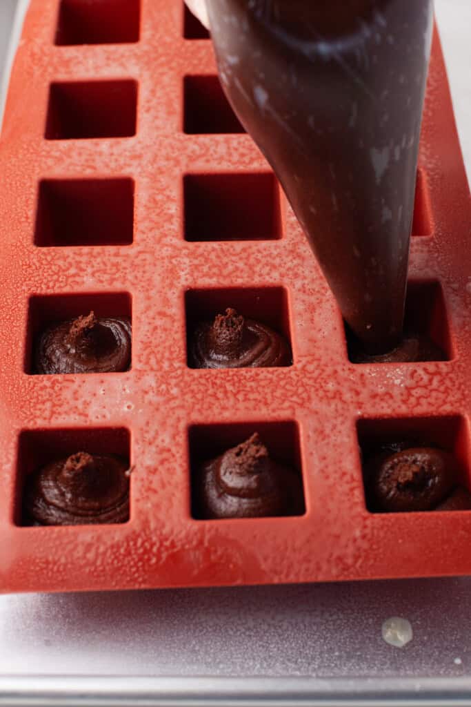 Overhead view of filling brownie bite molds with brownie batter.