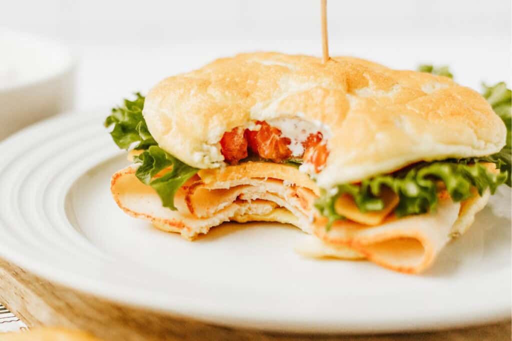 Fluffy cottage cheese cloud bread sandwich with turkey, cheese, lettuce, and tomato, bite taken