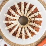Copycat Nothing Bundt Cake carrot cake with cream cheese frosting and chopped pecans on a white plate