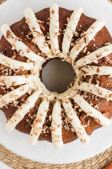 Copycat Nothing Bundt Cake carrot cake topped with cream cheese frosting petals and chopped pecans