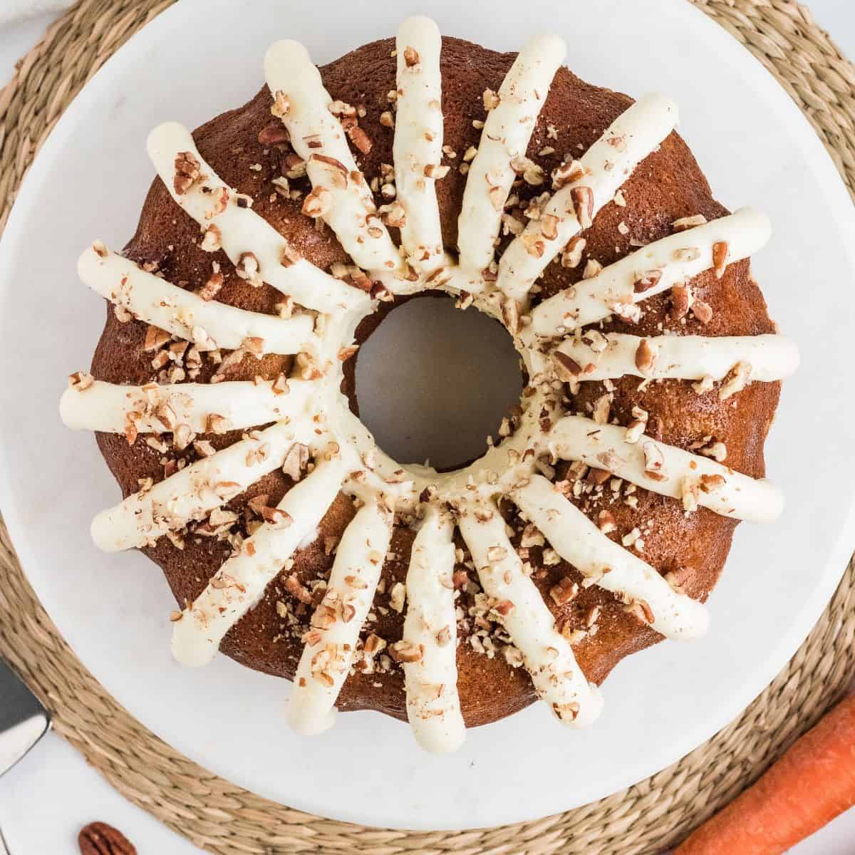 Copycat Nothing Bundt Cake carrot cake topped with cream cheese frosting petals and chopped pecans