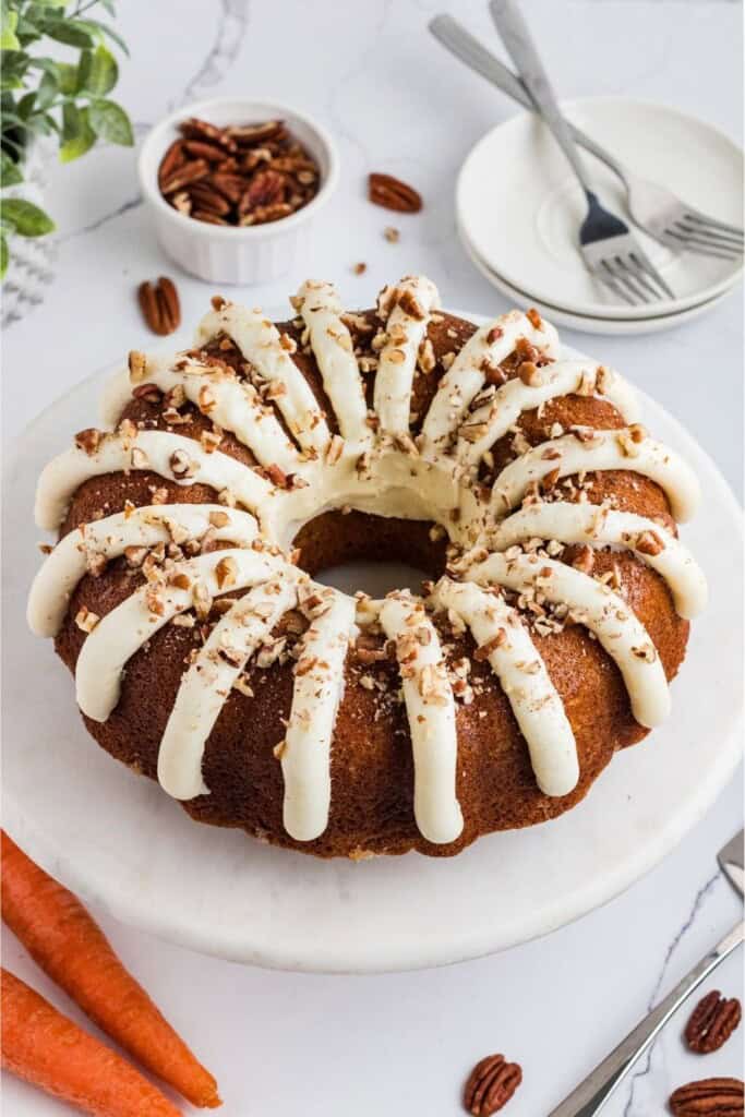 Copycat Nothing Bundt Cakes carrot cake styled with fresh carrots and pecans for serving