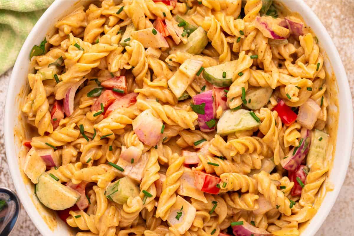 Overhead view of creamy BBQ pasta salad in a white serving bowl, ready to serve at a summer cookout