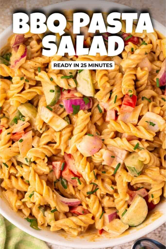 Overhead view of creamy BBQ pasta salad in a white serving bowl with rotini, bell pepper, cucumber, and chives, with text overlay reading Creamy BBQ Pasta Salad Easy Summer Side Dish