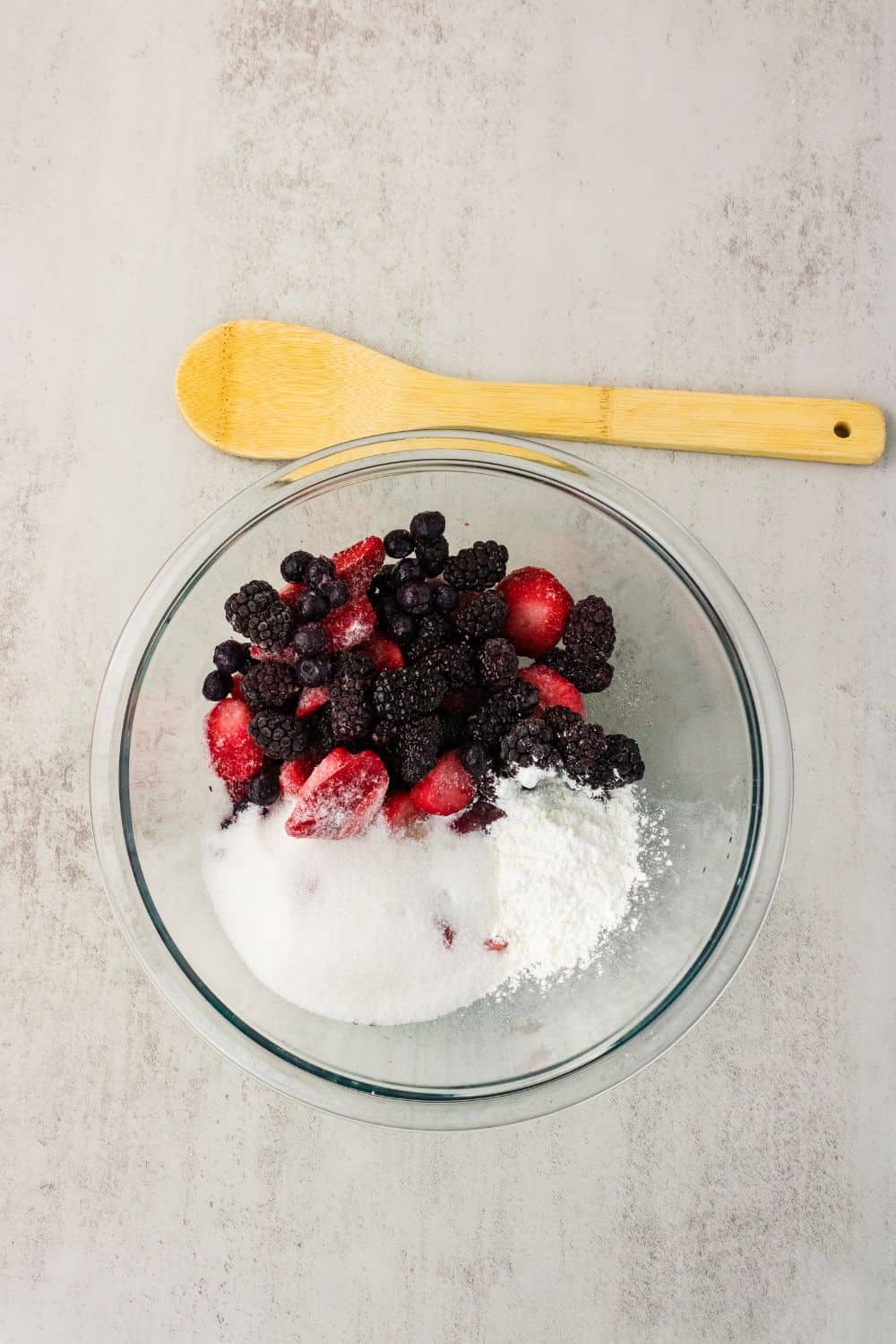Mixed berries, sugar, and cornstarch in a glass bowl before mixing