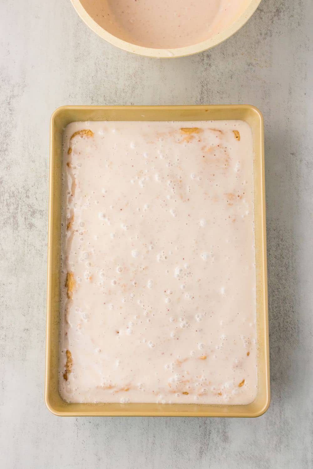 Dairy-free strawberry milk soak poured over fresh strawberry cake with fork holes