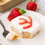 Fresh strawberry cake slice with whipped cream and fresh strawberry garnish
