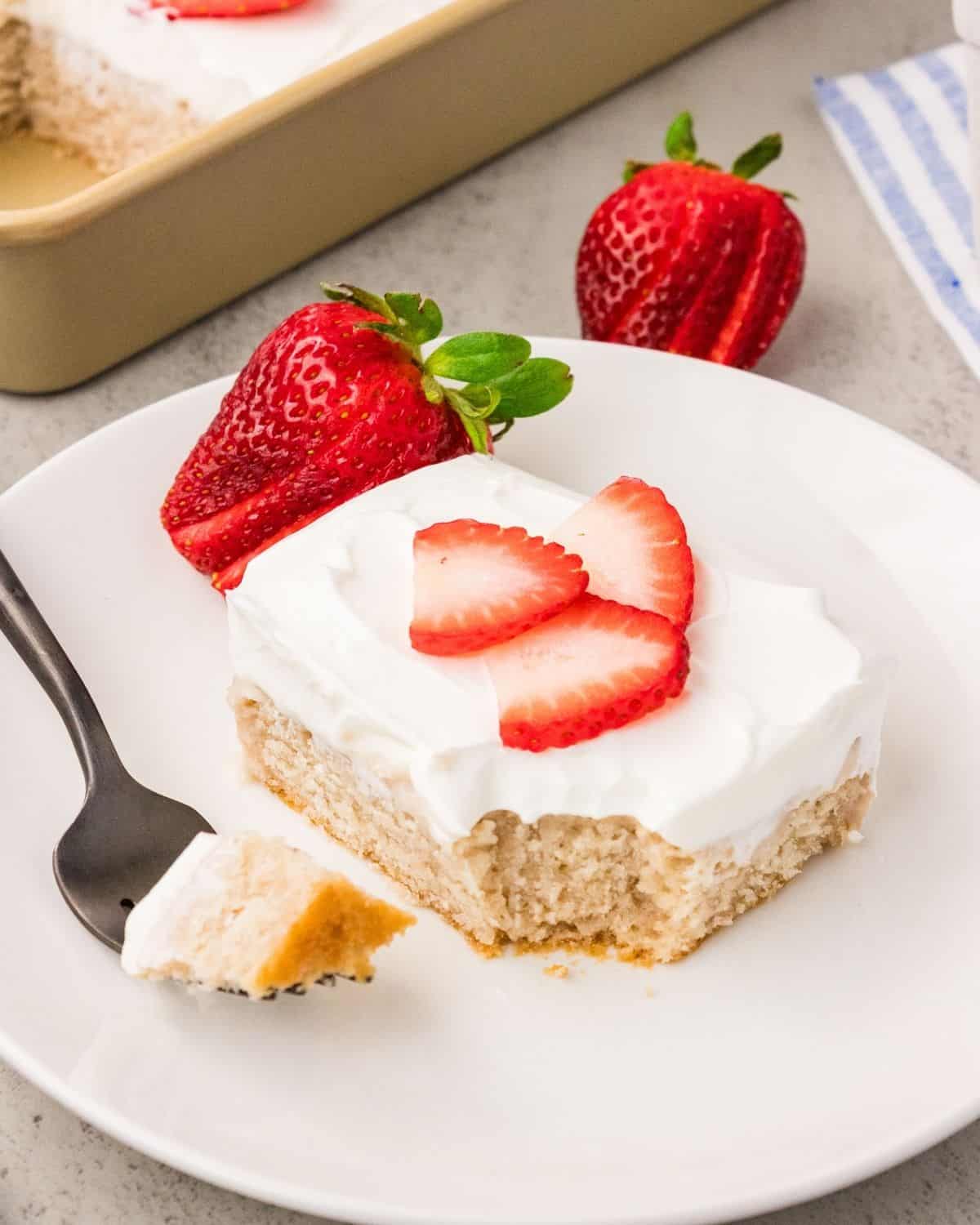 Fresh strawberry cake slice with whipped cream and fresh strawberry garnish
