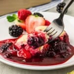 Berry cobbler with berries surrounding it on a fork