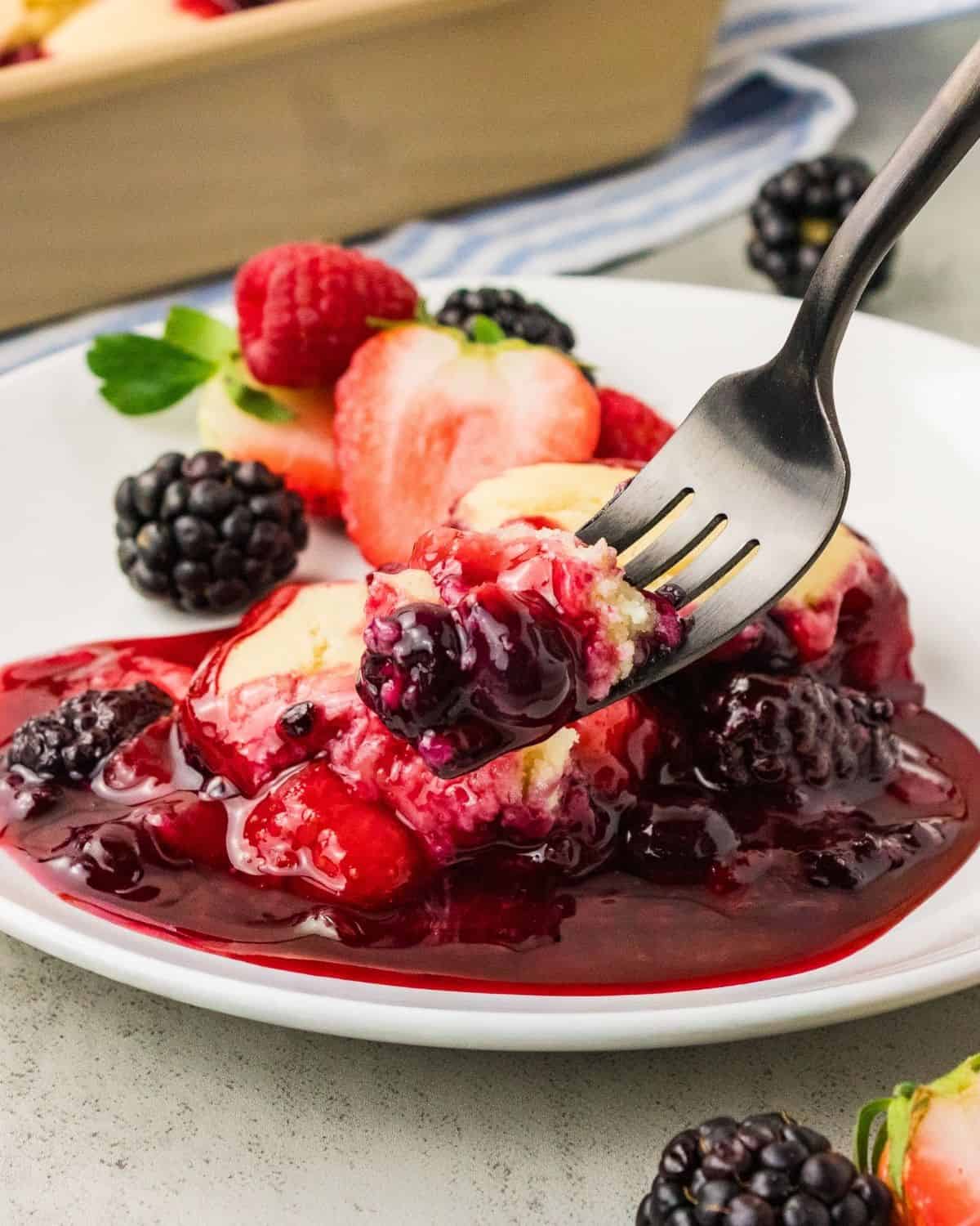 Berry cobbler with berries surrounding it on a fork