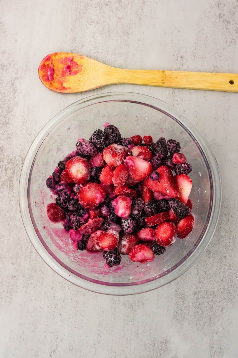 Mixed berries, sugar, and cornstarch in a glass bowl before mixing
