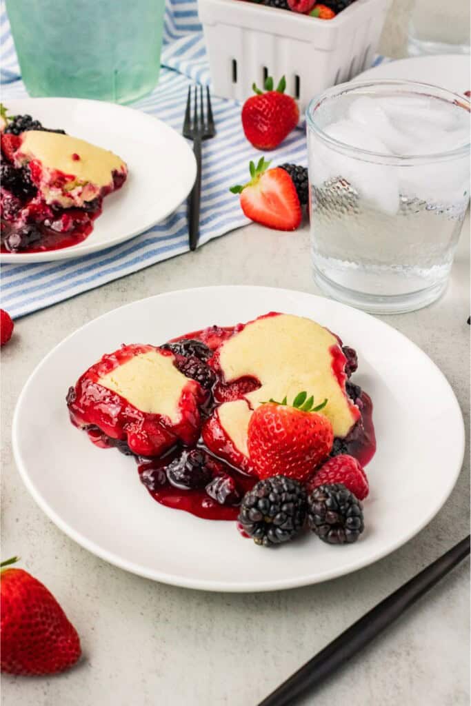 Spoonful of vegan gluten free berry cobbler with juicy mixed berries and golden biscuit topping