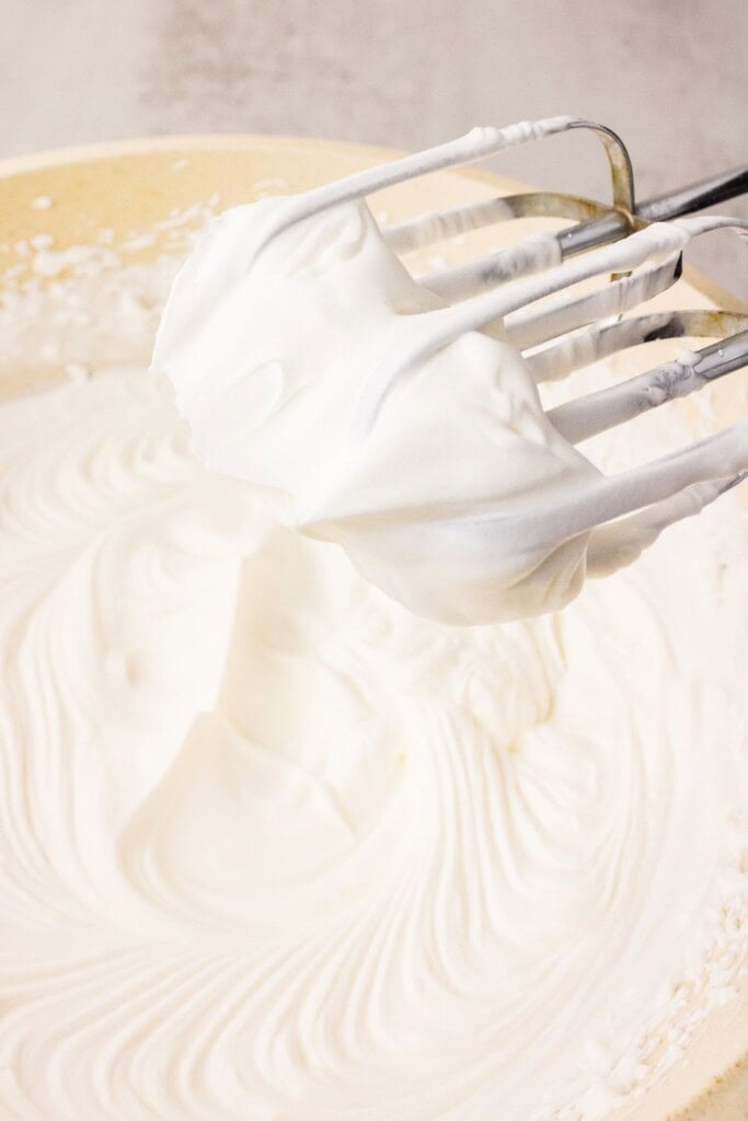 Dairy-free whipped coconut cream beaten to stiff peaks for strawberry cake topping