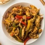 Air fryer chicken fajitas served in a white bowl with warm tortillas