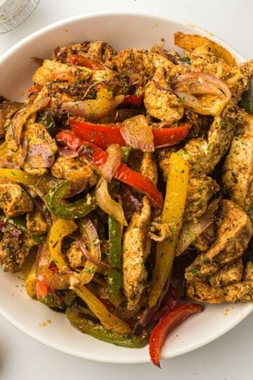 Bowl of air fryer chicken fajitas garnished with parsley and lime featured image