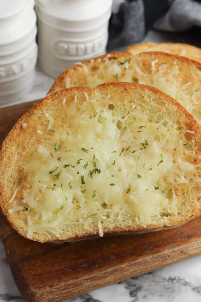 air fryer garlic bread slices with melted cheese and parsley on a wood board