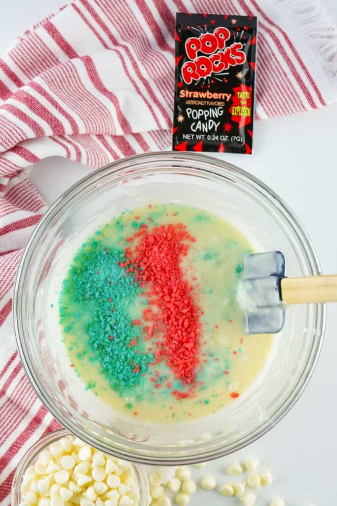 Red and blue Pop Rocks being folded into white chocolate fudge