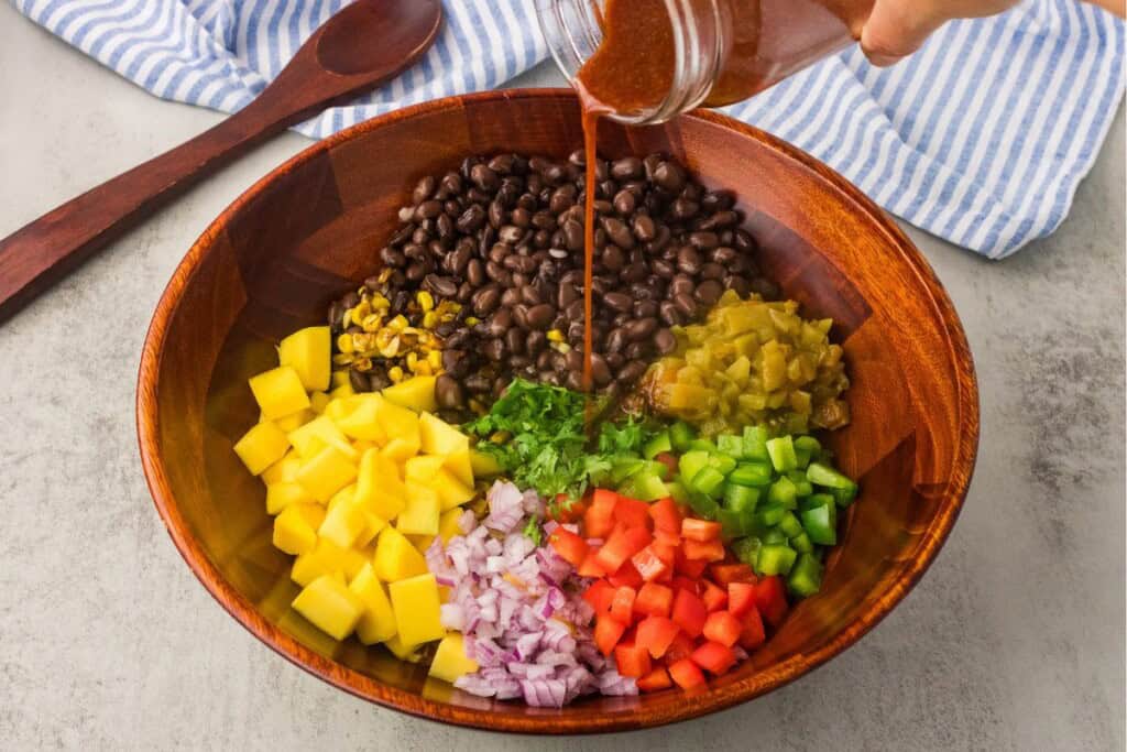 mango black bean salad pouring dressing