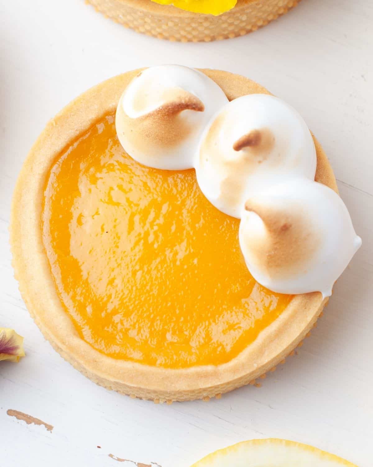 Mini lemon meringue tart with torched Italian meringue peaks and an edible pansy