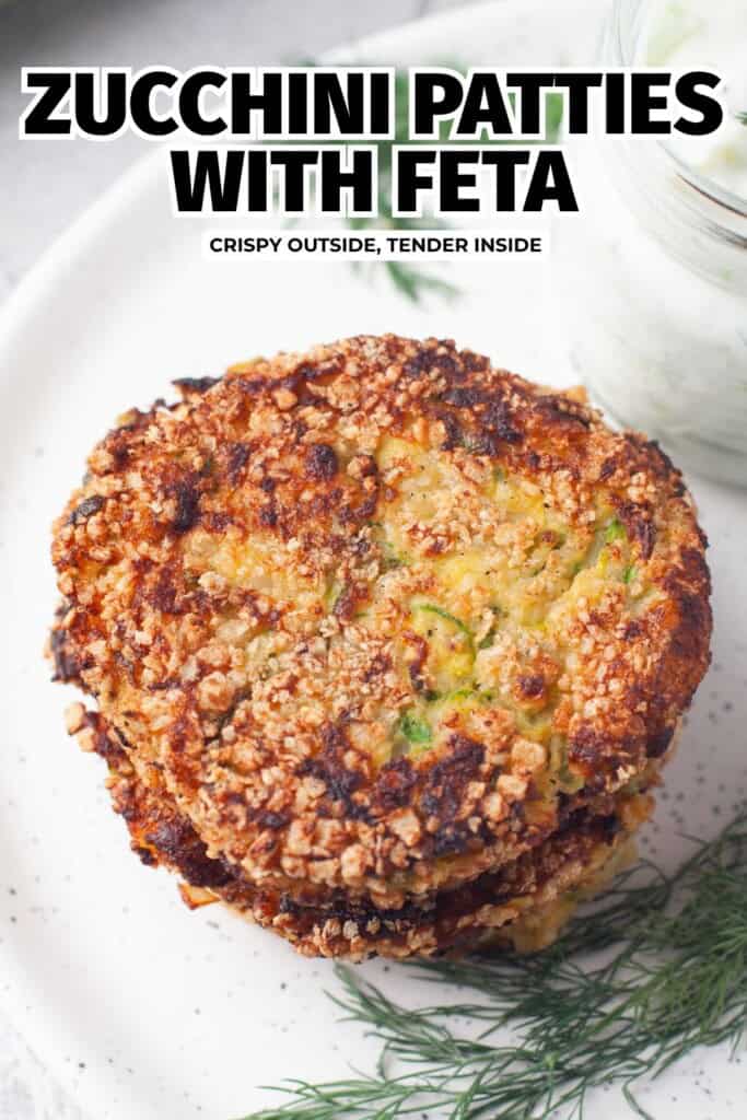 Two crispy zucchini patties with feta next to a jar of homemade tzatziki sauce