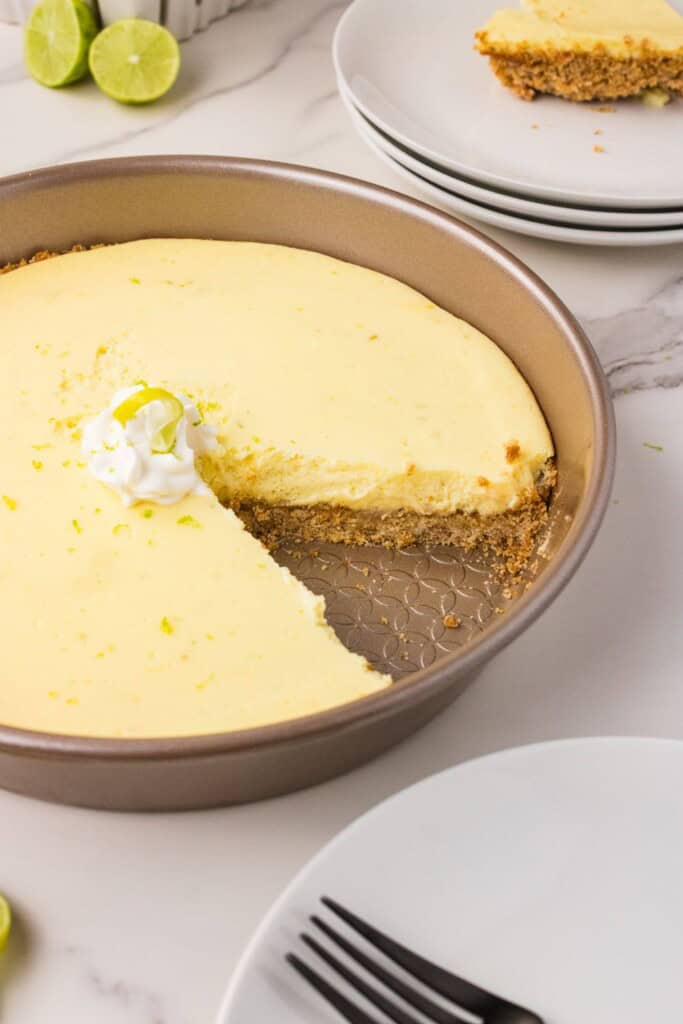 Easy key lime pie with bottled key lime juice in the pan with a slice removed and whipped cream