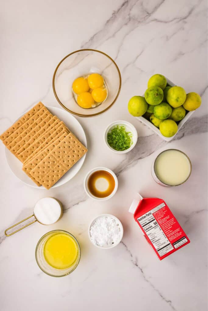 Key lime pie ingredients including key limes, egg yolks, graham crackers, and sweetened condensed milk